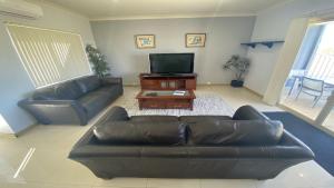 a living room with a leather couch and a flat screen tv at Unit 24 Seafront Estate in Jurien Bay