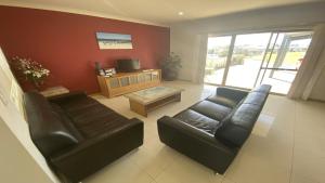 Sala de estar con 2 sofás de cuero y TV en Unit 58 Seafront Estate en Jurien Bay