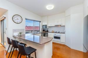 a kitchen with a large counter and a clock on the wall at Southern Waves in Port Fairy