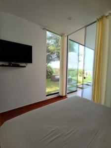 a bedroom with a large bed and a large window at Bungalow VerdeMar con Jacuzzi Frente al Mar in Vichayito