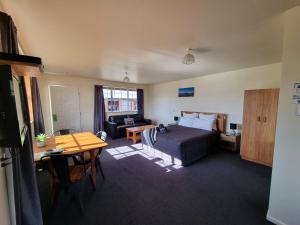 1 dormitorio con cama, escritorio y mesa en Colonial Motel en Twizel