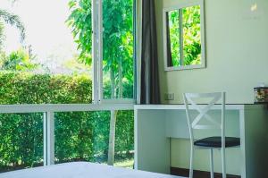 a bedroom with a desk and a chair next to a window at Sunee View Hotel in Chachoengsao
