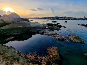 a body of water with rocks and the sunset at Lala Chill Homestay in Ke Ga