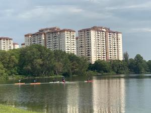 a group of people kayaking on a river with tall buildings at Homestay Ar Rayyan RESIDENSI LAGUNA BIRU in Rawang
