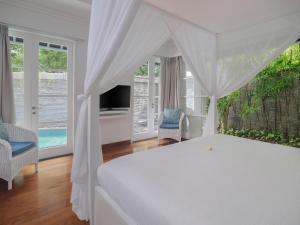 a bedroom with a white bed with a canopy at Peppers Seminyak in Seminyak