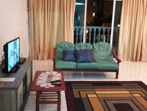 a living room with a green couch and a table at Pantai Puteri Kondominium in Kampong Bukit Darat