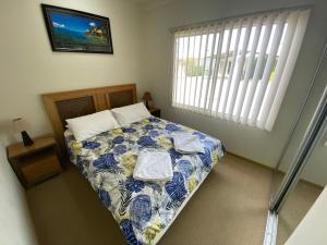 a bedroom with a bed with blue and white sheets and a window at Unit 29 Seafront Estate in Jurien Bay