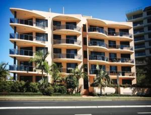 a large apartment building with palm trees in front of a street at Millenium 101 in Forster