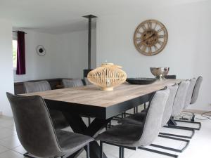 a dining room table with chairs and a clock on the wall at Luxury holiday home in Marchin with wellness in Marchin