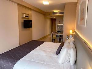 a bedroom with a large white bed in a room at Apart Cullinan - Centro de Brasília A210 in Brasilia
