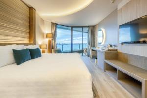 a hotel room with a large bed and a large window at Cape Dara Resort - SHA Plus in North Pattaya