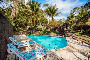 uma piscina com duas espreguiçadeiras e uma piscina em Pousada Canto da Mata Ilhabela em Ilhabela