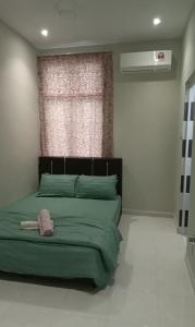 a bedroom with a green bed with a pink hat on it at NZ Villa Roomstay in Kangar