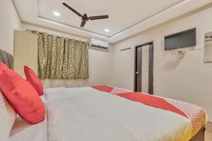 um quarto com uma cama com almofadas vermelhas e uma televisão em Hotel Ruby Grand Opp Apollo Hospital Kondapur em Kondapur