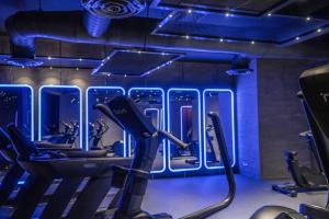 a gym with cardio equipment and blue lights at The House Hotel Al Khiran in Al Khīrān