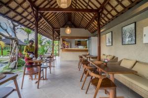 a woman standing in a restaurant with tables and chairs at Gerindem Cottages in Ubud