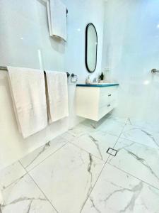 a white bathroom with a sink and a mirror at Hinchinbrook Resorts Management Pty Ltd in Lucinda
