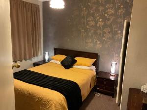 um quarto com uma cama com lençóis amarelos e almofadas amarelas em Bungalow on Centre em Invercargill