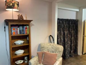 ein Wohnzimmer mit einem Stuhl und einem Bücherregal in der Unterkunft Bungalow on Centre in Invercargill