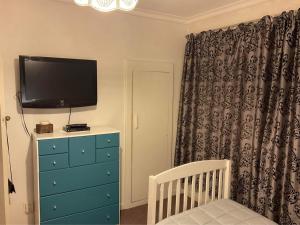 ein Schlafzimmer mit einem TV und einer Kommode mit einem Kinderbett in der Unterkunft Bungalow on Centre in Invercargill