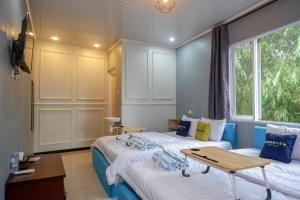um quarto com duas camas e uma mesa e uma janela em Urbanview Hotel Umbrella Dieng by RedDoorz em Kalibeber