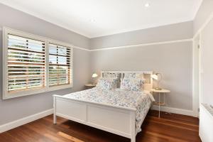 a white bedroom with a bed and a window at Alleura House in Leura