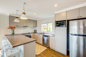 a kitchen with white cabinets and a stainless steel refrigerator at Boutique by Jervis Bay by Experience Jervis Bay in Vincentia