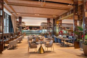 a restaurant with tables and chairs and a bar at Asawin Grand Convention Hotel in Bangkok