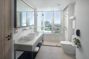 La salle de bains est pourvue de 2 lavabos et d'une grande fenêtre. dans l'établissement Miracle Grand Convention Hotel, à Bangkok