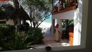 a woman in a white dress standing on a balcony at Red Monkey Beach Lodge in Jambiani