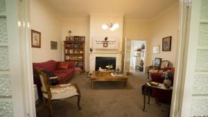 a living room with a red couch and a fireplace at Rose Pine Cottage at Leura in Leura