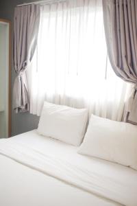 a bed with white pillows in front of a window at Wesa Home Place in Khon Kaen