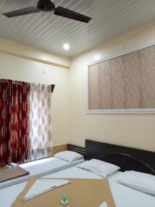 a room with two beds and a ceiling fan at Hotel Yogiraj in Shirdi