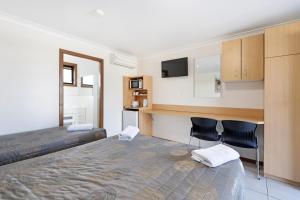 a bedroom with a bed and two chairs and a desk at Palm Valley Motel in Tarro