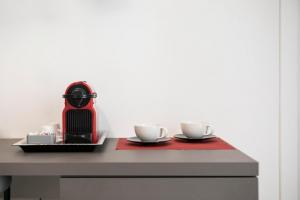 Bespoke Roma Suites في روما: آلة قهوة حمراء مع كوبين على طاولة