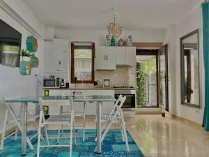 ママイア・ノルドにあるArcadia Apartament Mamaia Nordの白いキャビネット、ガラスのテーブルと椅子付きのキッチンが備わります。