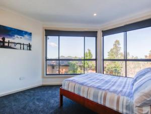 a bedroom with a bed and large windows at A Vista in Forster
