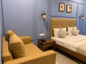 Hotel Radha krishna في أناند: غرفه فندقيه بسرير واريكه