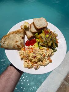 una persona sosteniendo un plato de comida con ensalada y pan en The Seles Boutique Hotel, en Matemwe