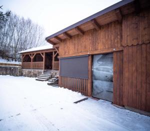 ein Holzgebäude mit einer Garage im Schnee in der Unterkunft Penzion Samoty in Železná Ruda