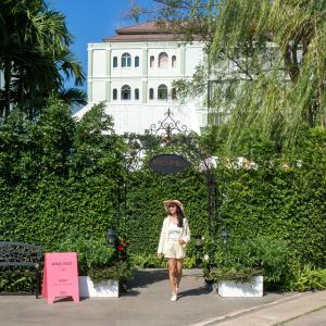 uma mulher a atravessar uma sebe em frente a um edifício em Ang Pao Hotel - SHA Extra Plus em Cidade Phuket