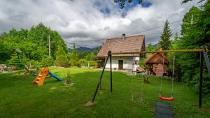 a yard with a playground with a slide and a house at Chalet House Olga in Crni Lug