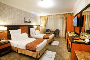 a hotel room with two beds and a television at Al Azhar Hotel Jeddah in Jeddah