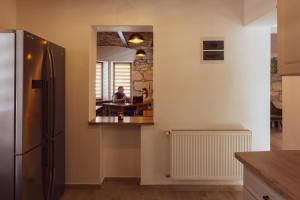 a kitchen with a refrigerator and a person sitting at a table at Pensiunea Violin Panzió in Băile Tuşnad