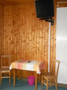 ジェラールメにあるHotel Les Sapinsのテーブル、椅子2脚、テレビが備わる客室です。
