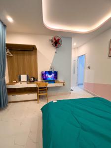 a bedroom with a bed and a desk with a television at EURO HOUSE in Da Lat