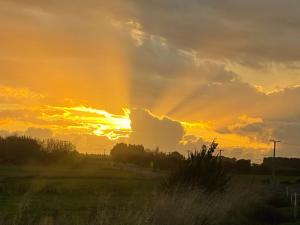 una puesta de sol con el sol brillando a través de las nubes en Big Fully Equipped 3BRM Quiet Farm House Near Beach & 12 min to Town en Riverton