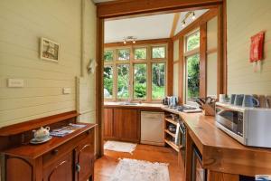 une cuisine avec des placards en bois et un comptoir avec un four micro-ondes dans l'établissement Idlehour Cottage, à Katoomba