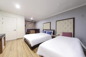 a hotel room with two beds and a door at Central Hotel in Changwon