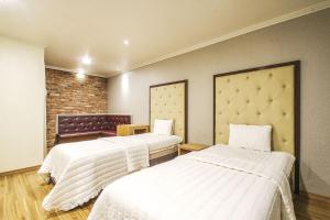 昌原的住宿－Central Hotel，一间设有两张带白色床单的床的房间